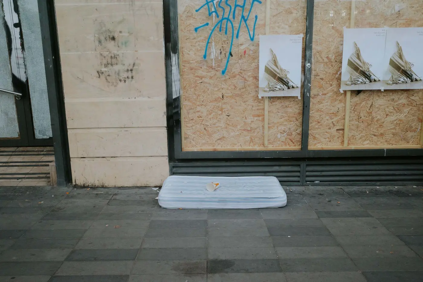 Eine weggeworfene Matratze liegt auf dem Gehweg vor einem vernagelten Ladenlokal