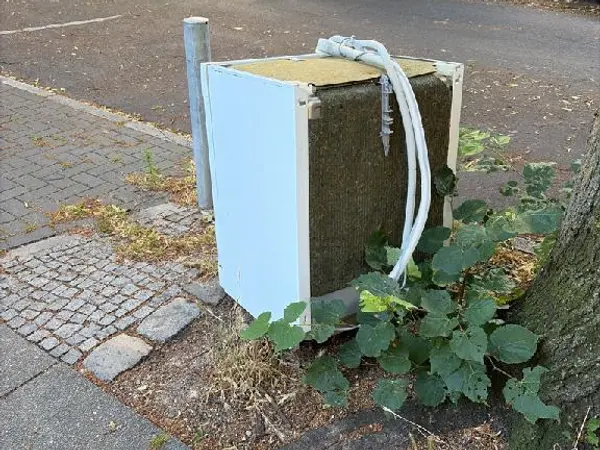 Ausgedientes Haushaltsgerät neben einem Straßenbaum