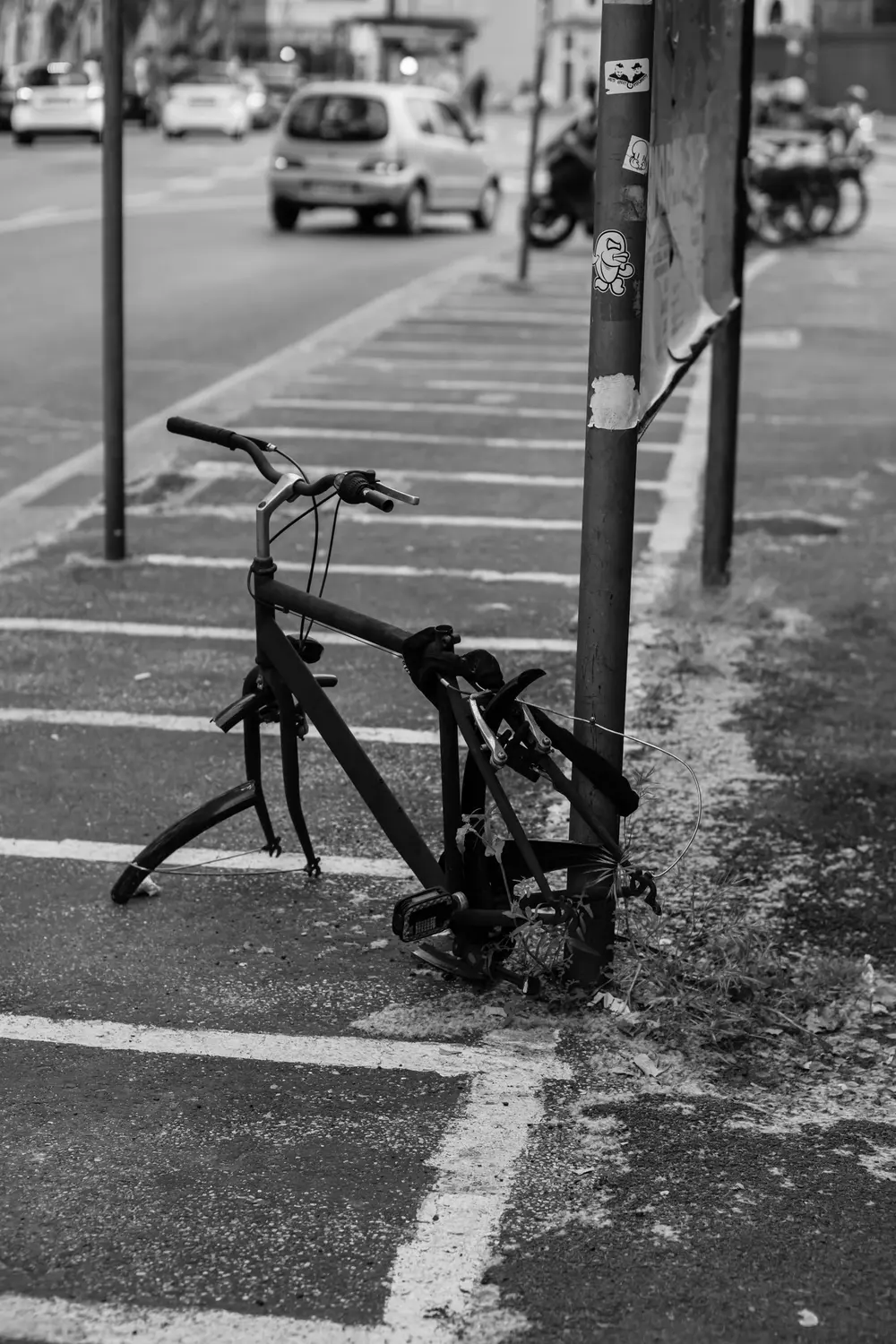 Ein Fahrrad ohne Vorderrad, an einen Laternenpfahl angeschlossen, auf einem Gehweg